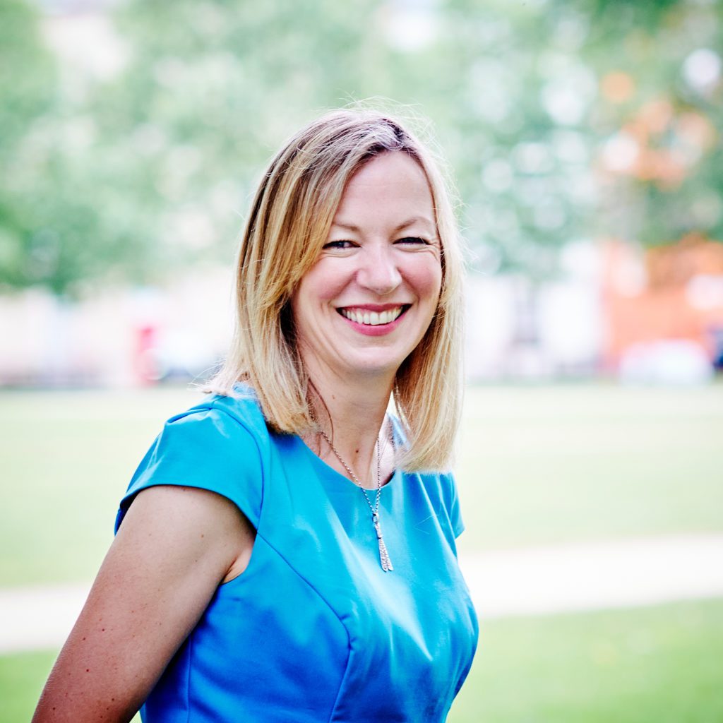 Claire Bloor the SARSAS CEO. She is smiling in a park. She wearing a blue top. She is a white women with blonde hair.