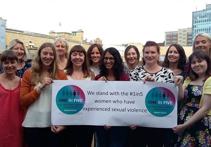 A group of women hold a campaign banner.