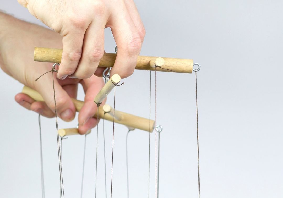 Puppet hands holding puppet strings