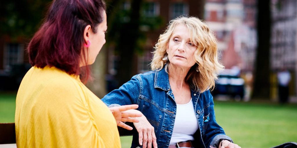 Two women talking on a bench in a park