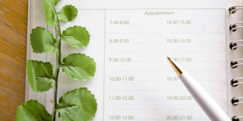 A paper calendar with a pen and a fake plant.