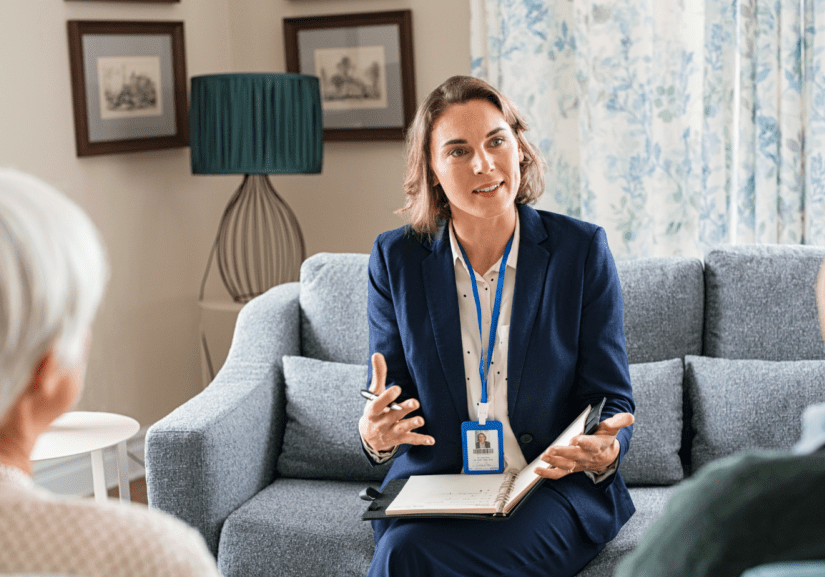 A female social worker is meeting with an older woman and man.