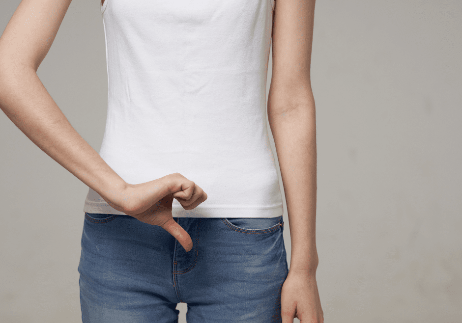 A woman giving a thumbs down sign over her groin.