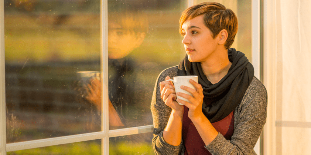 lady looking out window with mug in her hand
