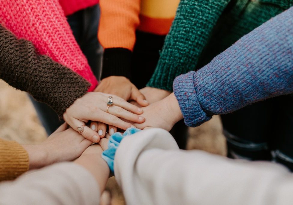 A shot of people's hands coming together in the middle of a circle.