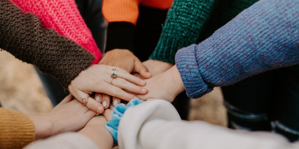 A shot of people's hands coming together in the middle of a circle.