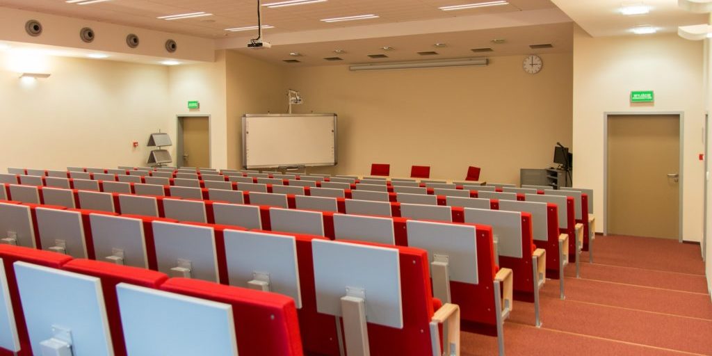 An empty lecture room with red chairs.