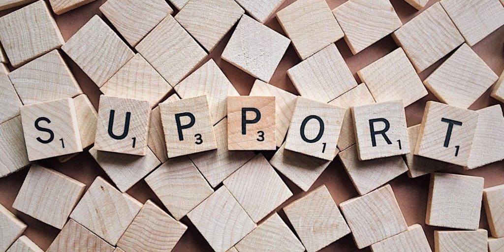 the word support put together using wooden scrabble pieces